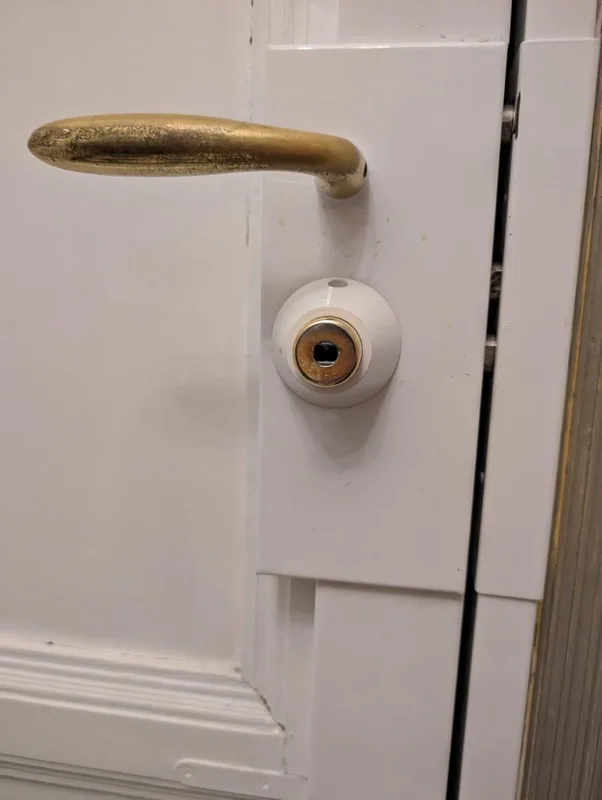Poignée laiton et protège-cylindre sur porte blanche